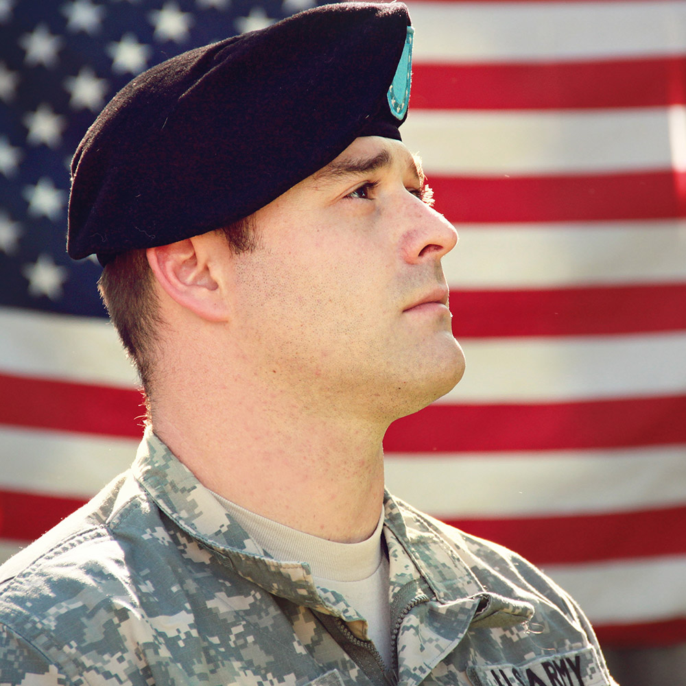 Soldier posing in front of American Flag.